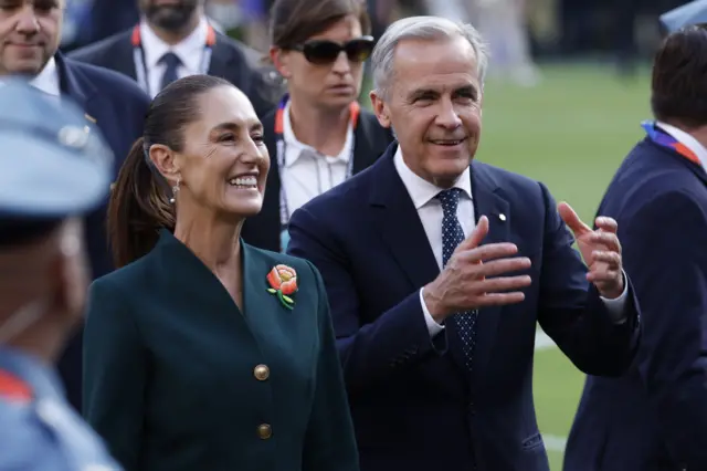 Claudia Sheinbaum y Jay Carney caminan por el campo después de la final en Nueva York.